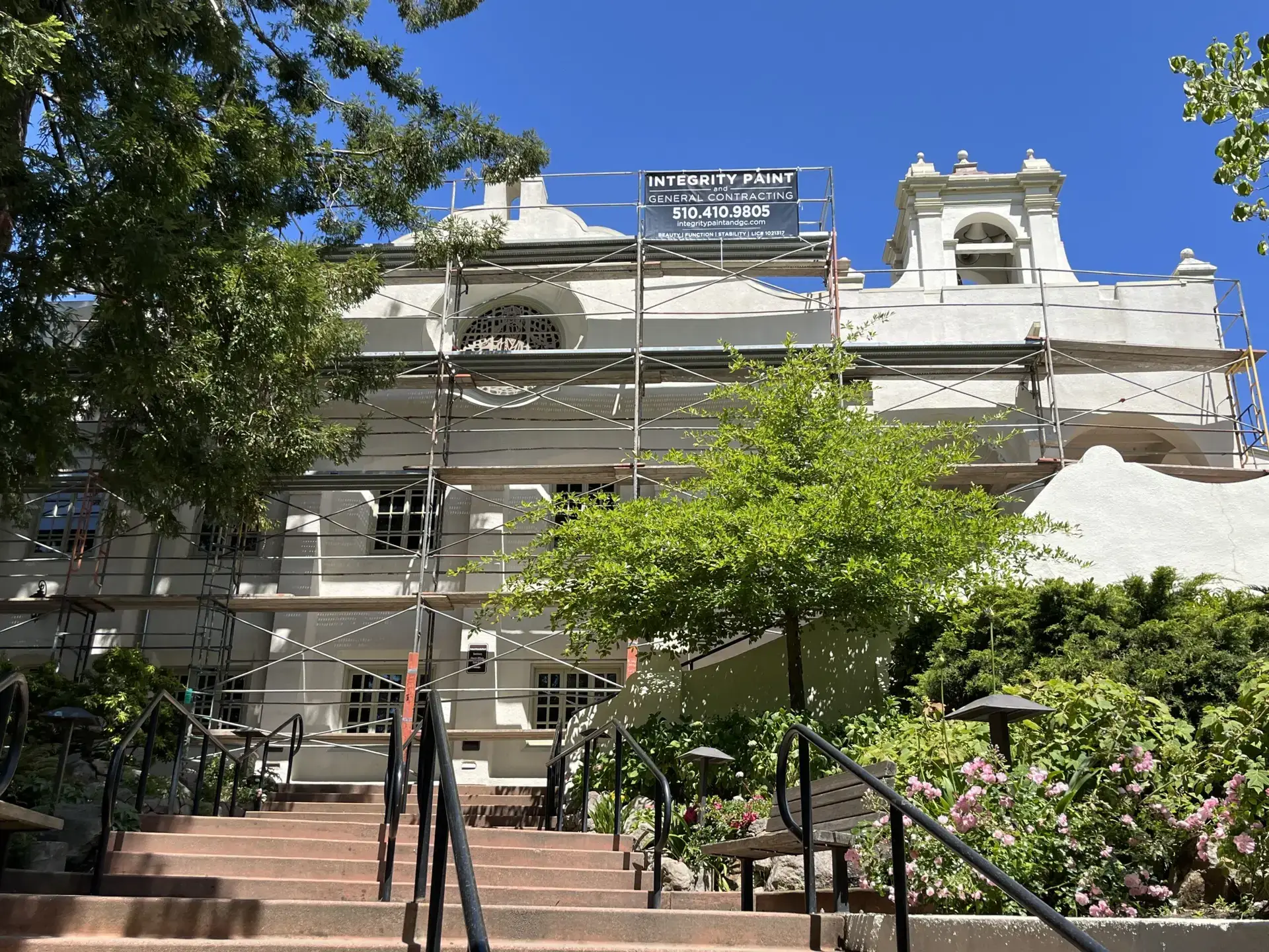 Integrity Paint and General Contracting banner on scaffolding during an exterior repaint of a multi-story stucco building